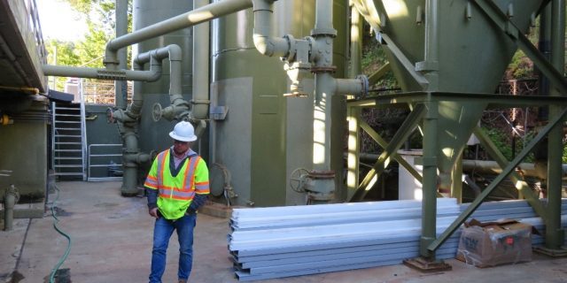 Worker standing next to sand filter.